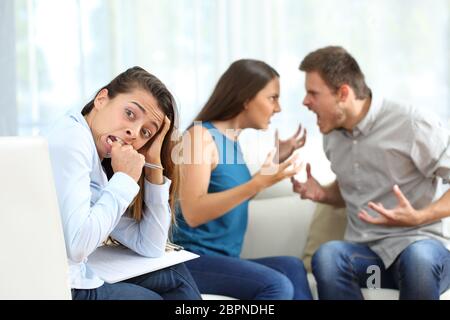 Giovane sostenendo e rompendo in su in una consulenza matrimoniale e la guida pazzo per il terapista in una casa. Impossibile la riconciliazione Foto Stock