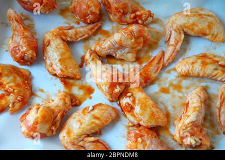 Ali di pollo su pergamena tegame coperto pronto per cuocere al forno Foto Stock