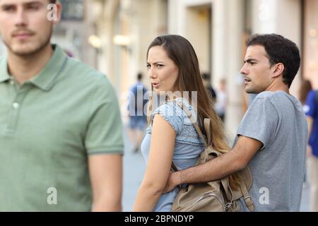 Donna disfedele che guarda un altro uomo e il suo ragazzo arrabbiato che la guarda per strada Foto Stock