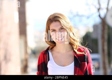 Vista anteriore verticale di un millenario ragazza adolescente in piedi che guarda in telecamera in strada Foto Stock