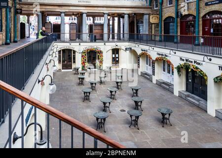 Una guardia di sicurezza guarda giù ai negozi e ristoranti chiusi nel mercato di Covent Garden durante un fine settimana durante il blocco pandemico del coronavirus, Londra, Regno Unito Foto Stock