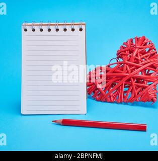 Aprire il notebook vuoto in linea e cuore rosso su sfondo blu Foto Stock