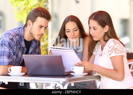 Tre studenti di felice apprendimento insieme lettura delle note in un coffee shop Foto Stock