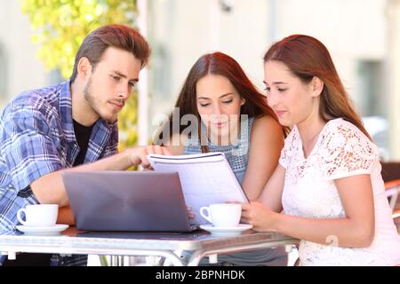 Tre concentrati gli studenti di confrontare gli appunti in un coffee shop Foto Stock