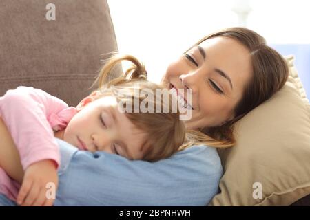 In prossimità di una mamma orgogliosa guardando il suo bambino dorme sdraiato su un divano nel soggiorno di casa Foto Stock