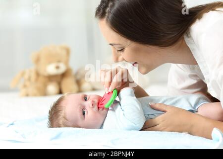 Felice madre dando un amaro al suo bambino su un letto Foto Stock