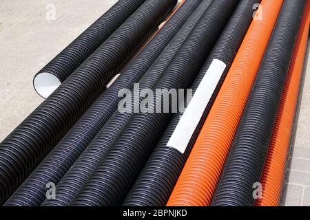 nuovi tubi in plastica arancione e nero sul cantiere Foto Stock