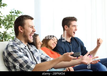 Uomini eccitati di guardare la tv e annoiati fidanzate seduta su un divano nel salotto di casa Foto Stock