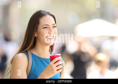 Unica donna felice passeggiate a piedi e in possesso di una granita in strada Foto Stock