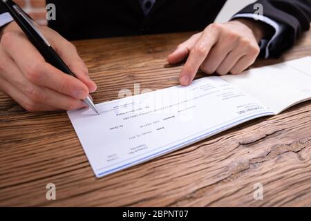 Close-up di un imprenditore la mano a verificare la firma con la penna in ufficio Foto Stock