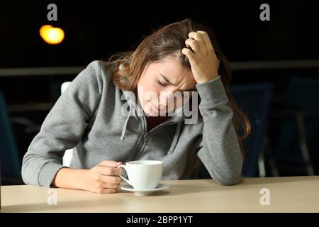 Ritratto di un triste teen lamenta da soli in una caffetteria nella notte Foto Stock