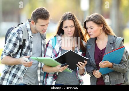 Tre studenti confuso controllo note su carta prima di esame Foto Stock