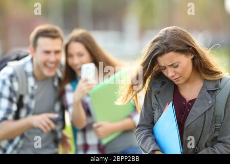 Vittima di bullismo essendo video registrati su uno smartphone da compagni di classe in strada con un background non focalizzato Foto Stock