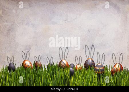 Uova di Pasqua con le orecchie di coniglio carino su erba verde su sfondo bianco. Spazio per il testo Foto Stock