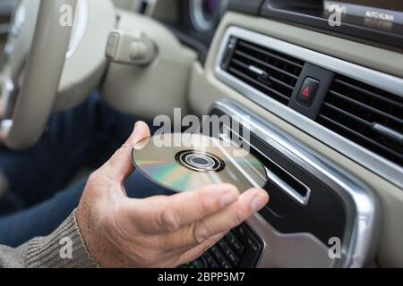 Uomo di riproduzione di musica in auto hic - inserimento HI-FI CD nel suo lettore CD slot (SHALLOW DOF) Foto Stock