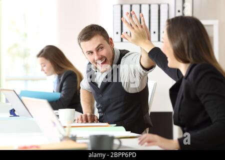 Due collaboratori entusiasti per celebrare il raggiungimento dando cinque in ufficio Foto Stock