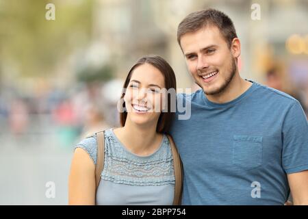 Vista frontale di una coppia felice che cammina sulla strada e guarda lontano Foto Stock