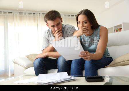 Preoccupato per il giovane la lettura di una lettera seduta su un divano nel salotto di casa Foto Stock