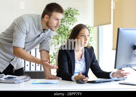 Turbare gli imprenditori cercano di lavorare in linea con un computer desktop guardando il monitor in ufficio Foto Stock