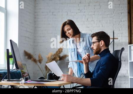 Fotografo e designer grafico che lavora in ufficio con computer portatile, monitor, tavoletta grafica e tavolozza colori. Creazione di un team che discute le idee in Foto Stock