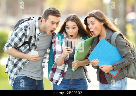 Tre studenti stupito il controllo sul contenuto di linea su un telefono intelligente in strada Foto Stock