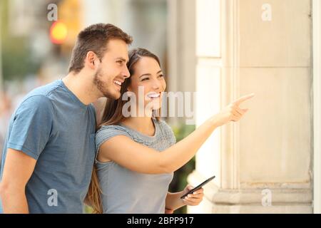 Un paio di acquirenti che guardano uno storefront e indicano i prodotti per strada Foto Stock