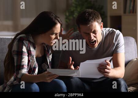 Furious matura la lettura di una lettera seduto su un divano a casa Foto Stock