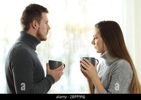 Vista laterale verticale di un arrabbiato giovane uno davanti all'altro alla ricerca di distanza dopo la tesi a casa Foto Stock