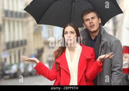 Ritratto di un disgustato giovane infastiditi in un giorno di pioggia sotto la pioggia e un ombrello in inverno Foto Stock