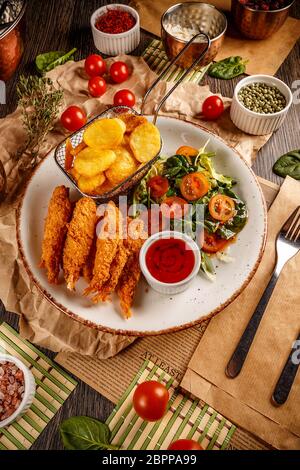 Gamberi in tempura con peperoncino piccante salsa, insalata fresca e patate fritte. Piatti da pub Foto Stock