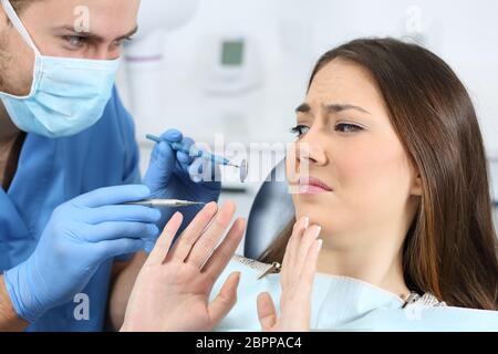 La paura di un paziente con un medico tenta di esaminare la sua in un studio dentistico Foto Stock