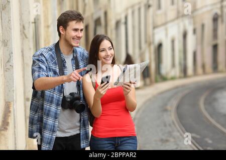 Paio di felici turisti sightseeing confrontando la guida online e la mappa in un vecchio town street Foto Stock