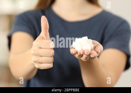 Vista frontale ravvicinata di una donna una mano che trattiene i cubetti di zucchero con il pollice fino a casa Foto Stock