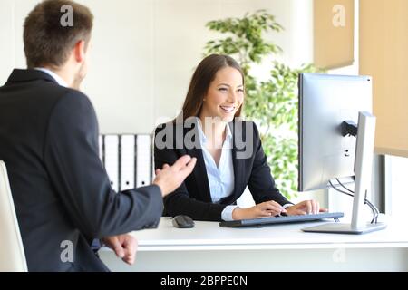 Agent partecipando a un client introducendo i dati in un computer desktop in ufficio Foto Stock