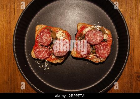 Vista dall'alto di due piccole bruschette con salame e funghi Foto Stock
