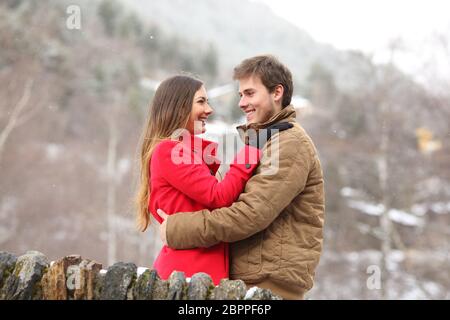 Coppia felice costeggiata cercando ogni altro in vacanza invernale su un ponte in pietra in montagna Foto Stock