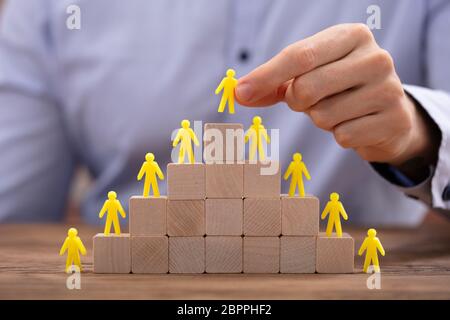 Close-up di mano di una persona immissione giallo figura umana permanente sulla sommità di una pila di blocchi Foto Stock