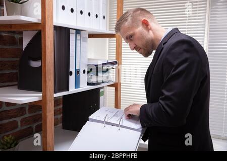 Close-up di un imprenditore di esaminare il documento fattura segretamente in Office Foto Stock