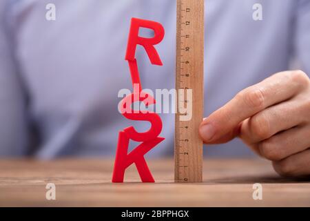 Close-up di persona della mano azienda righello di legno e Rosso parola rischio Foto Stock