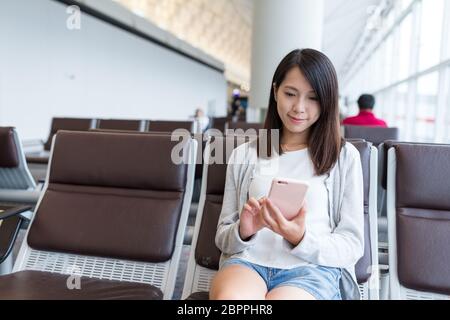 Donna su di telefono cellulare in aeroporto Foto Stock