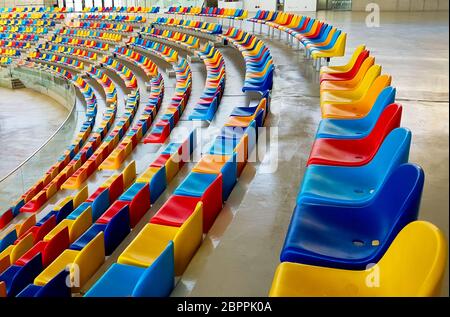 Panchine di colori diversi in uno stadio sportivo Foto Stock