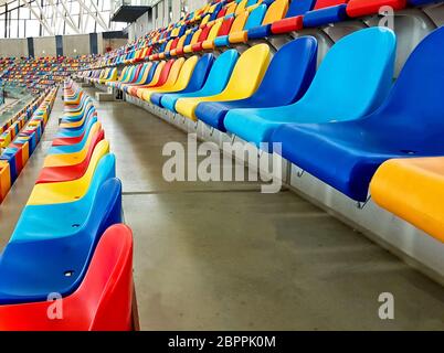 Panchine di colori diversi in uno stadio sportivo Foto Stock