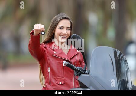 Felice acquirente del motociclo che mostra i tasti in telecamera per esterno Foto Stock