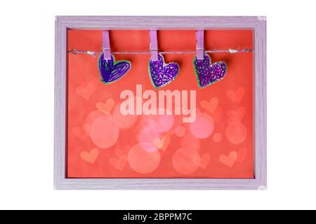 Dichiarazione d'amore con tre cuori decorativi su una plotessina in una cornice di legno con texture di sfondo rosso isolato su uno sfondo bianco. Mothe Foto Stock