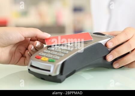 Primo piano di una mano donna che paga con un contatto meno carta di credito in un negozio di banco Foto Stock