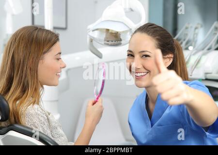 Ritratto di un cliente soddisfatto e dentista controllo risultati dentale in ufficio Foto Stock