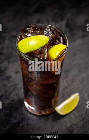 Fresche fatte Cuba Libre marrone con rum, cola e limone su sfondo nero Foto Stock