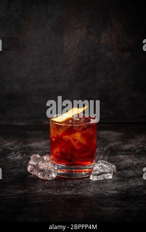 Negroni cocktail decorata con buccia di colore arancione su sfondo scuro Foto Stock