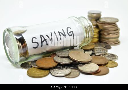 Etichetta di risparmio in un vasetto di vetro con monete fuoriuscita isolati su sfondo bianco Foto Stock