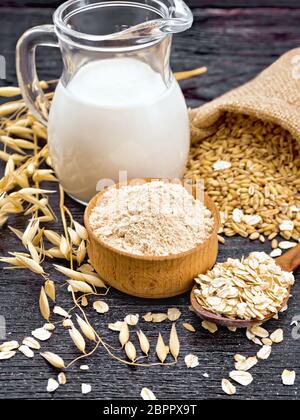 Avena la farina in una terrina il grano in un sacchetto, fiocchi d'avena in un cucchiaio, stocchi oaten sullo sfondo del pannello di legno Foto Stock